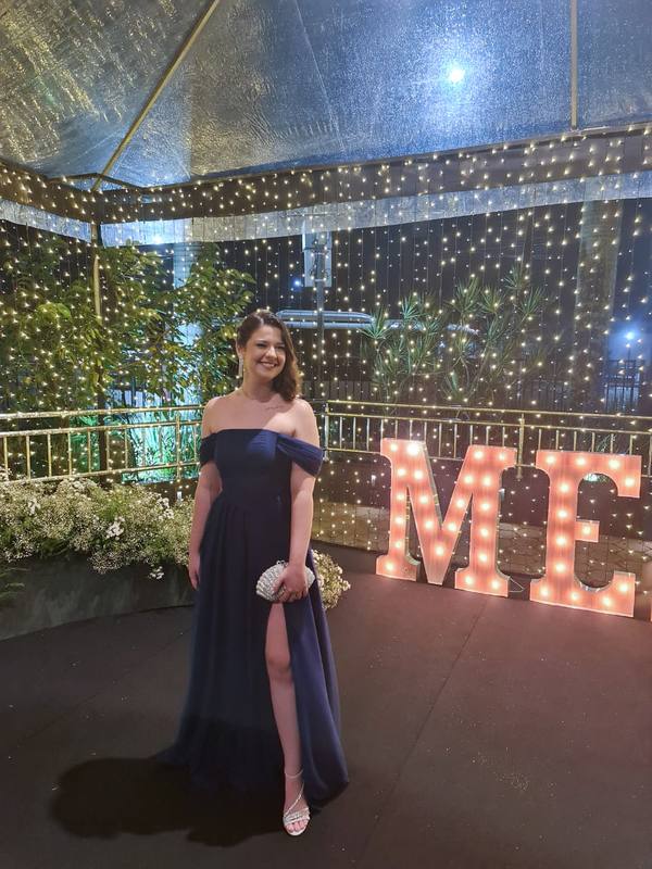 Vestido longo azul escuro fluido, com decote tomara que caia, mangas ombro a ombro e fenda lateral na saia.