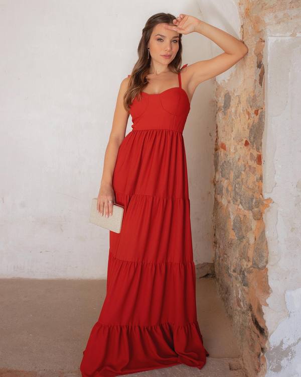 Vestido longo vermelho com alças finas, decote estruturado e saia fluida em camadas.