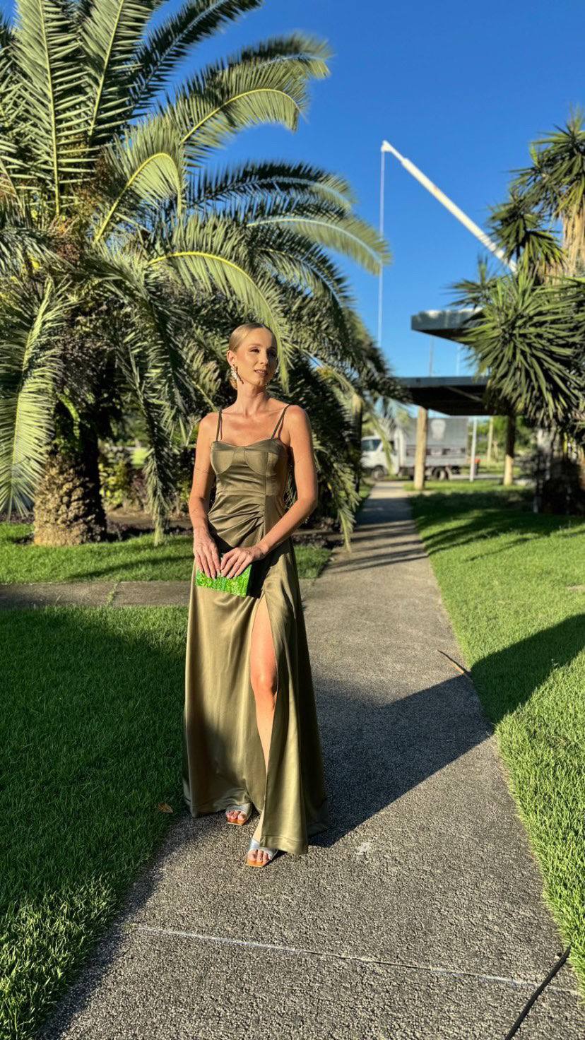 Vestido longo verde oliva de cetim, com alça fina, caimento fluido e fenda na saia.