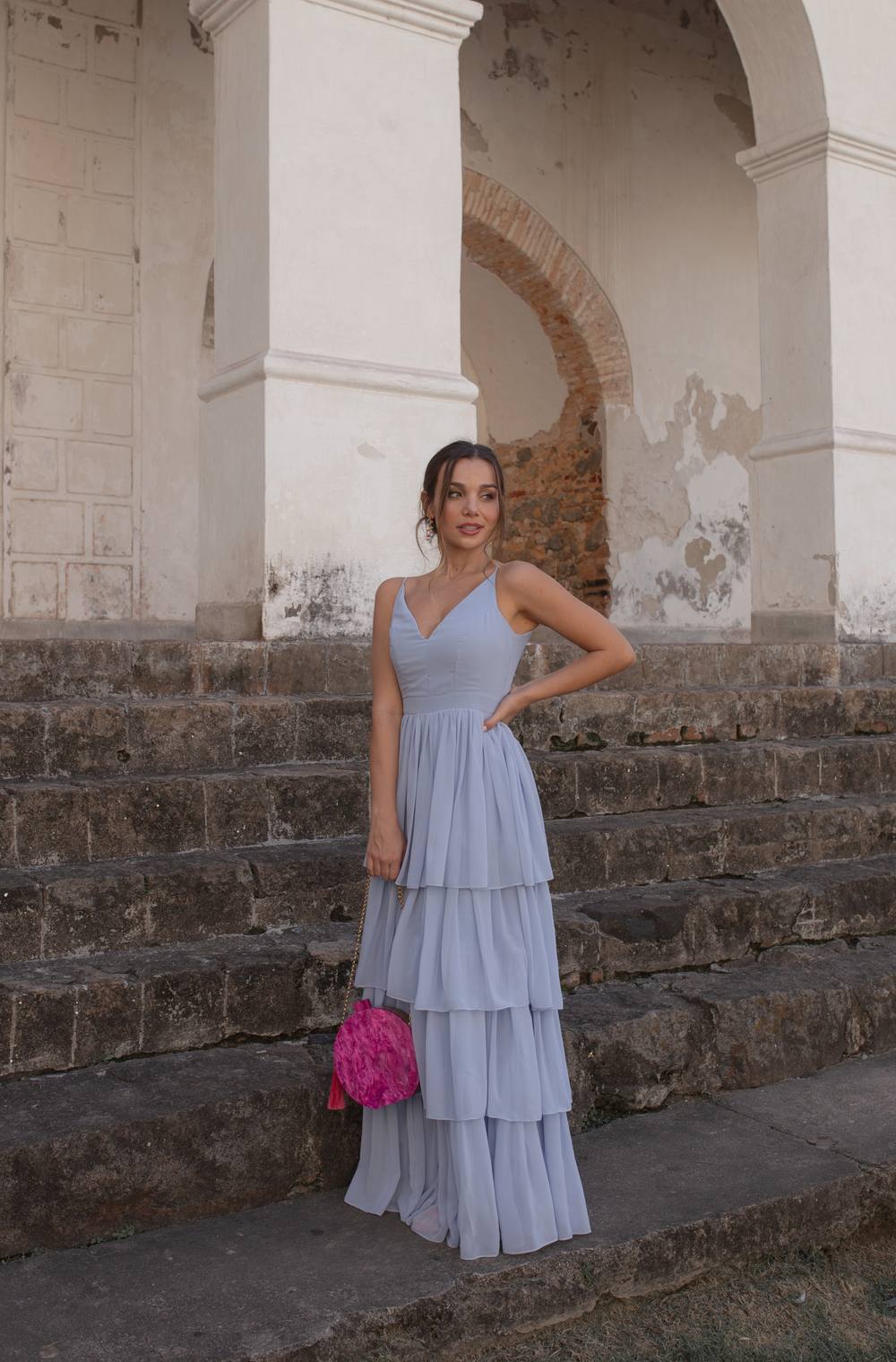 Vestido longo azul claro de tecido fluido, com alças finas, decote V e saia em camadas sobrepostas.