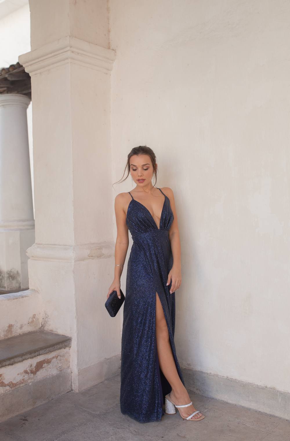 Vestido longo azul escuro com brilho, alças finas, decote V e fenda na saia.