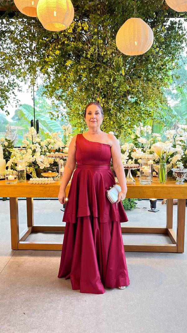 Vestido longo marsala em tecido encorpado, decote de um ombro, cintura definida e saia ampla com camadas.