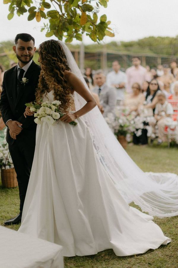 Vestido de noiva branco evasê, alça fina e cauda ao ar livre