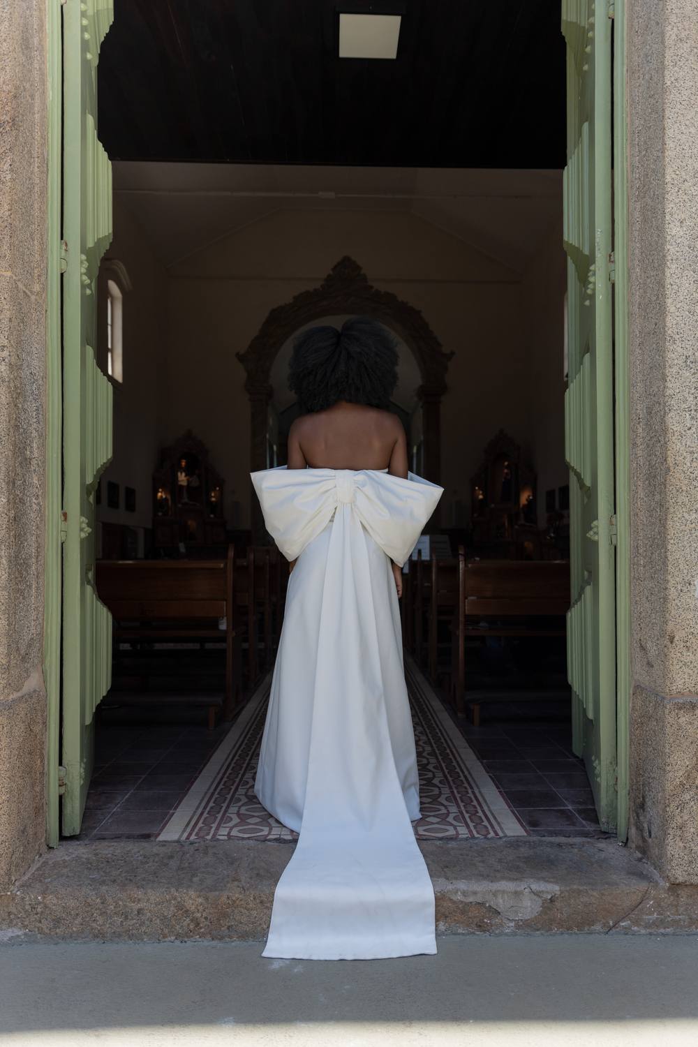 Vestido longo off-white tomara que caia com laço estruturado nas costas e caimento fluido.