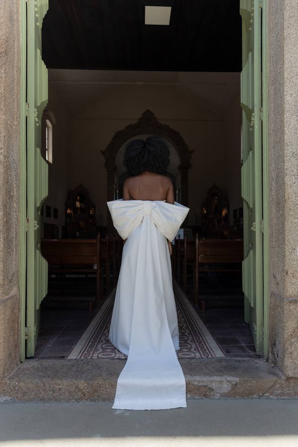 Vestido longo off-white tomara que caia com laço estruturado nas costas e caimento fluido.