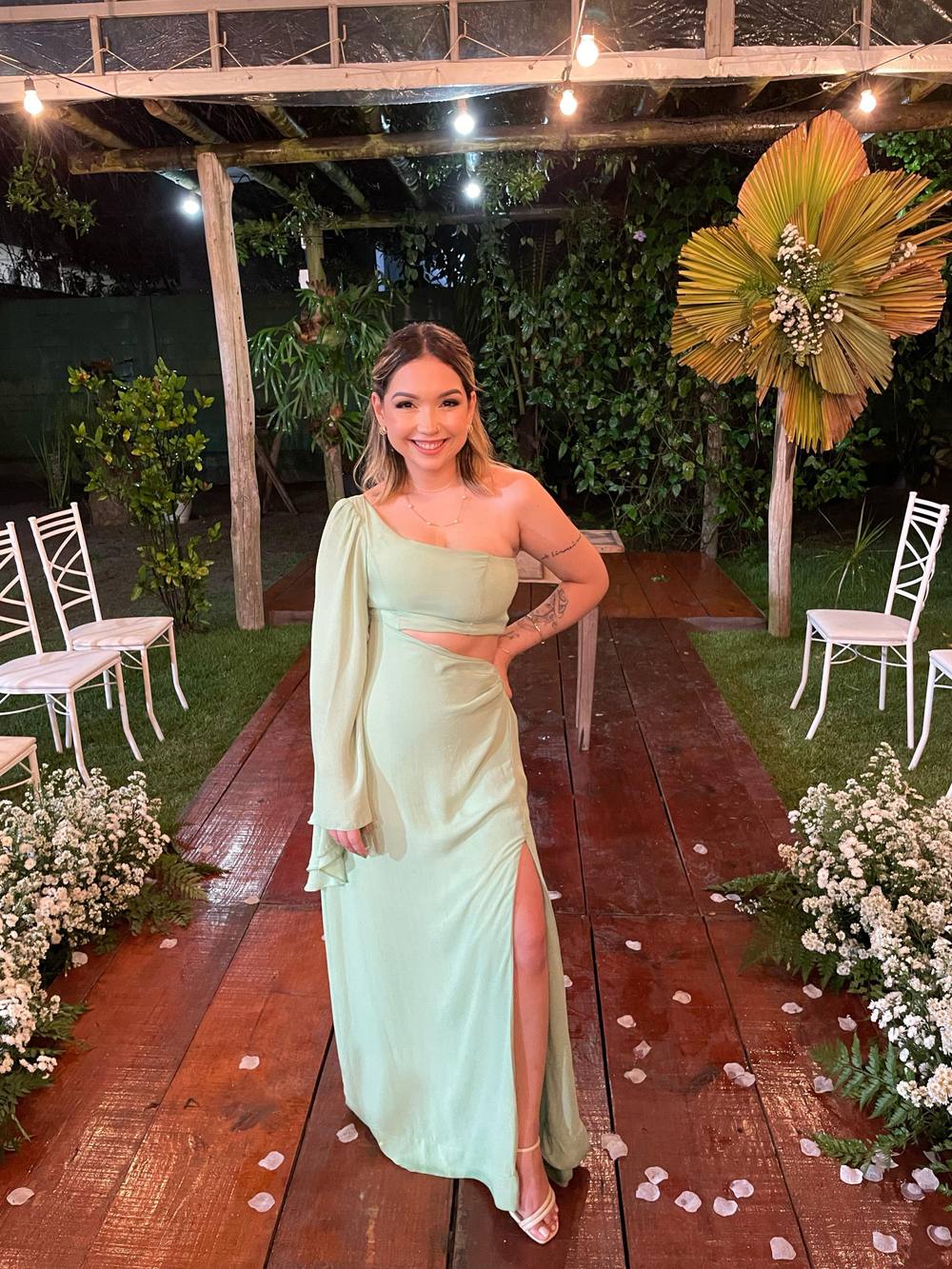Vestido longo verde claro em tecido leve, modelo de um ombro só com manga longa, recorte na cintura e fenda lateral.