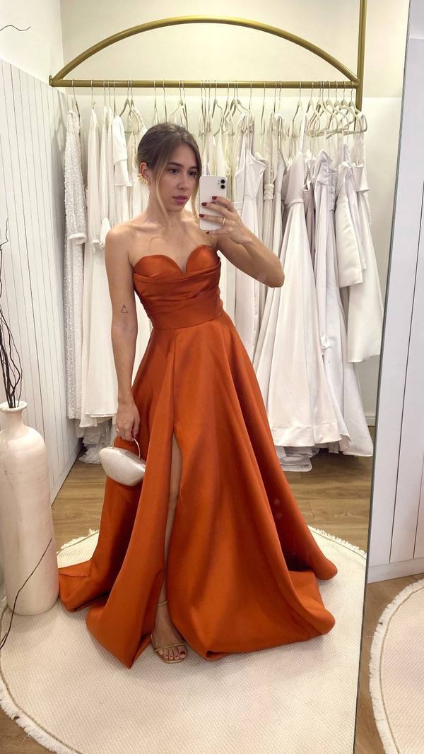 Vestido longo terracota em tecido acetinado, decote tomara que caia estruturado, saia evasê e fenda lateral.