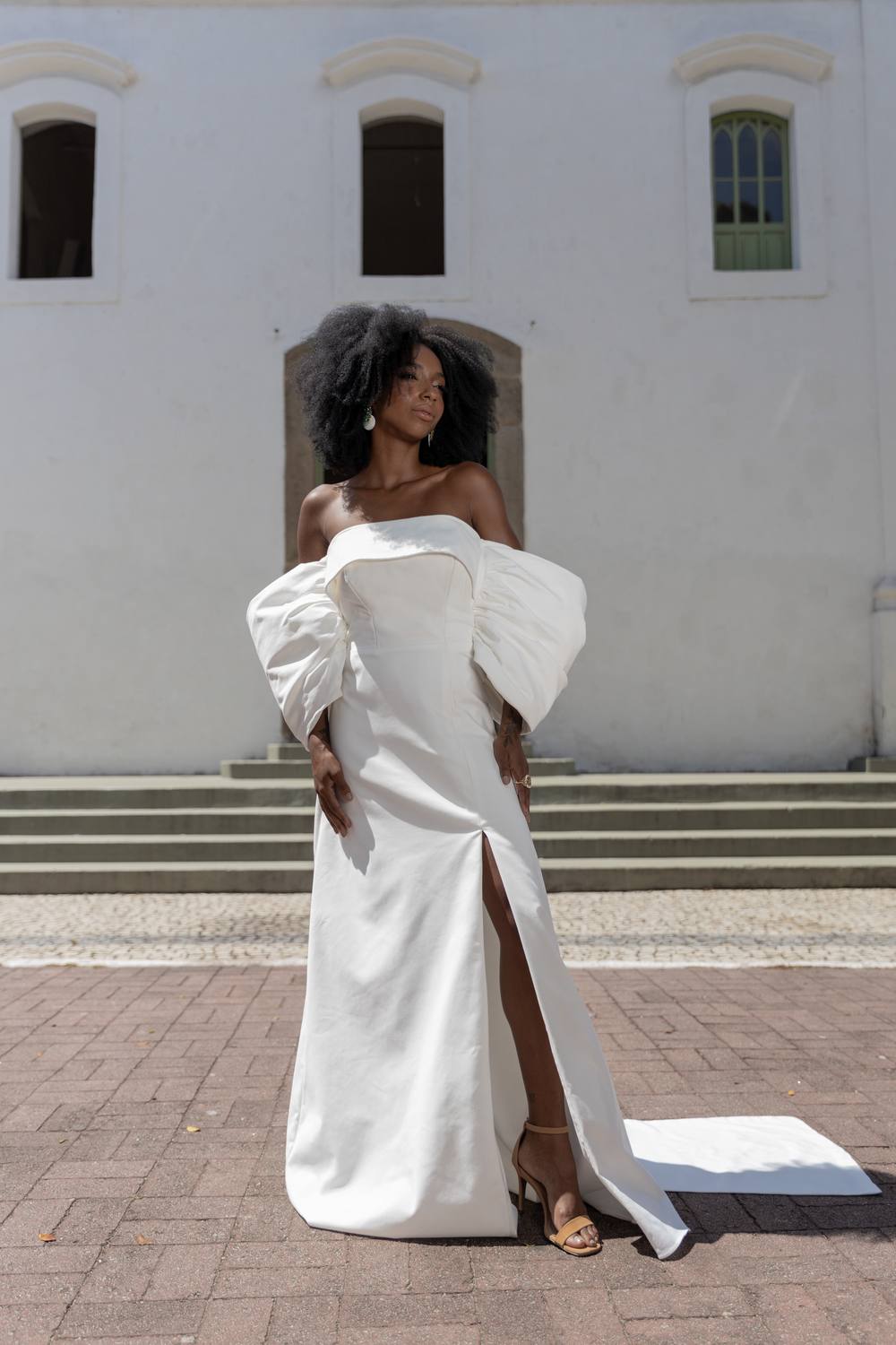 Vestido longo off-white tomara que caia com mangas bufantes volumosas e fenda frontal.