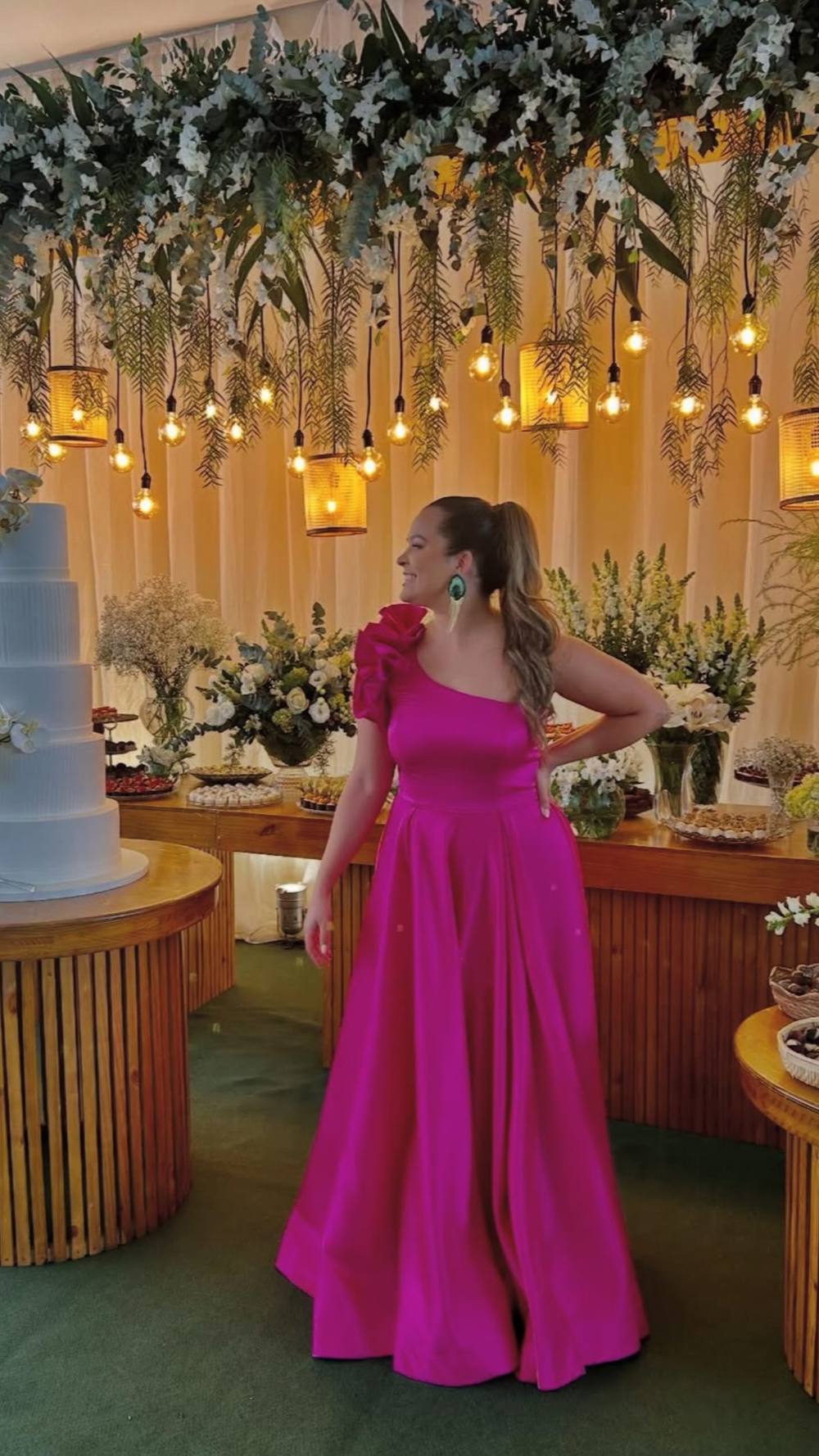 Vestido longo fúcsia de um ombro só com aplicação de babados e saia evasê com pregas.
