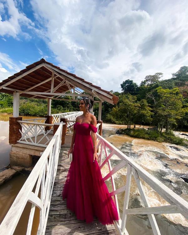 Vestido longo fúcsia de tule, decote tomara que caia com ombros caídos e saia fluida evasê.