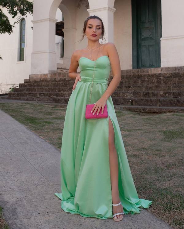 Vestido longo verde claro de cetim, tomara que caia, com saia evasê e fenda lateral.