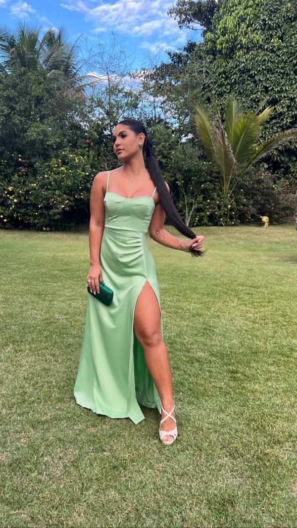 Vestido longo verde claro em tecido acetinado, de alças finas, detalhe franzido e fenda alta na saia.