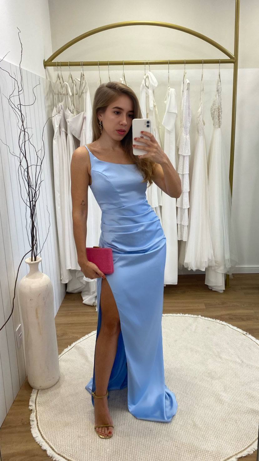 Vestido longo azul claro em tecido acetinado, com alças finas, drapeado na cintura e fenda lateral.
