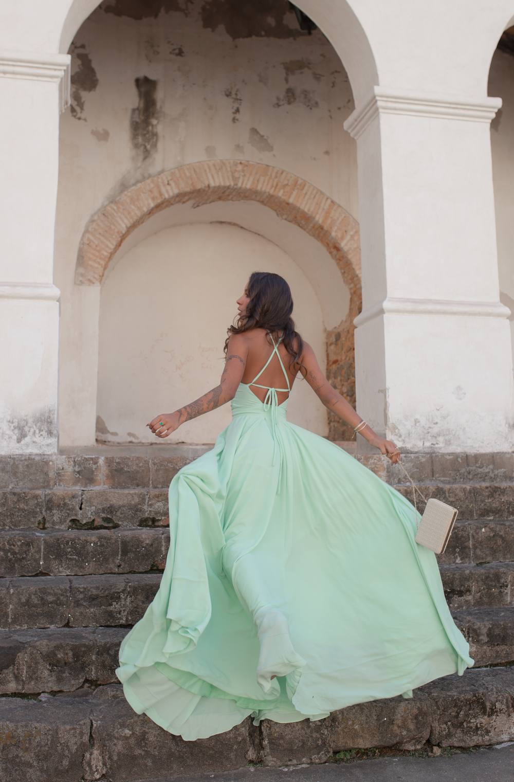 Vestido longo verde claro em tecido fluido, com alças finas cruzadas nas costas e saia ampla.