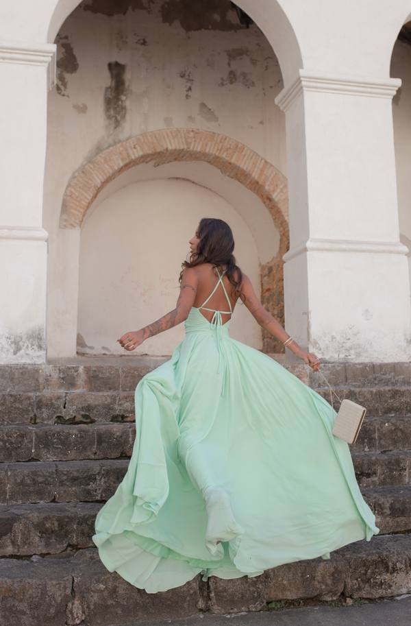 Vestido longo verde claro em tecido fluido, com alças finas cruzadas nas costas e saia ampla.