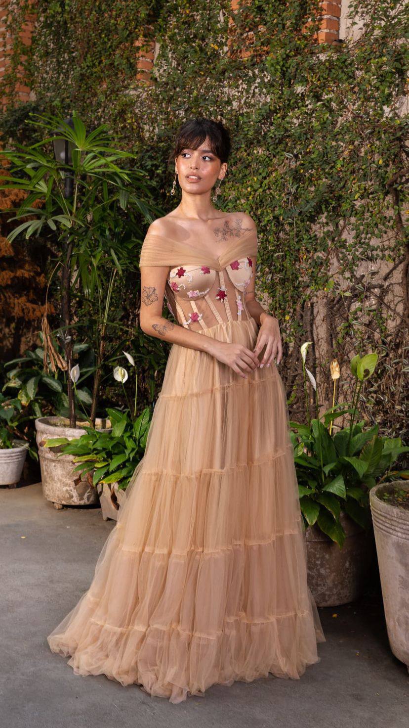 Vestido longo nude em tule com saia em camadas, decote ombro a ombro drapeado e corsete com aplicações bordadas.