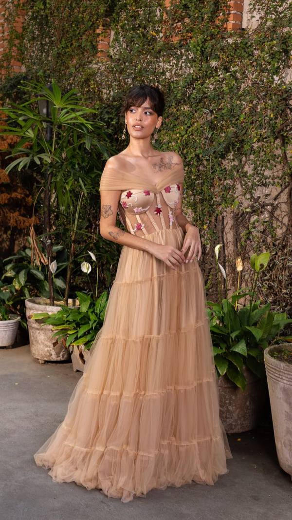 Vestido longo nude em tule com saia em camadas, decote ombro a ombro drapeado e corsete com aplicações bordadas.