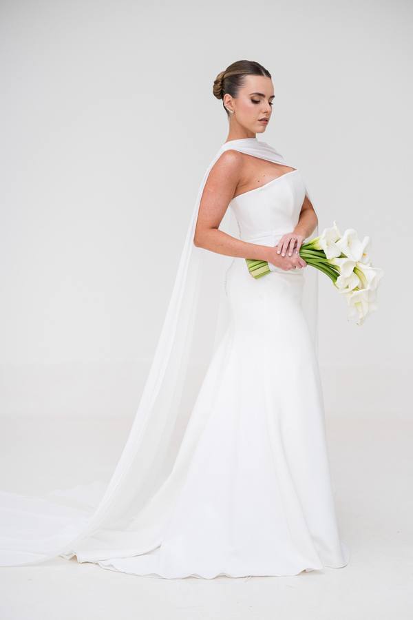 Vestido de noiva branco com capa de um ombro e cauda